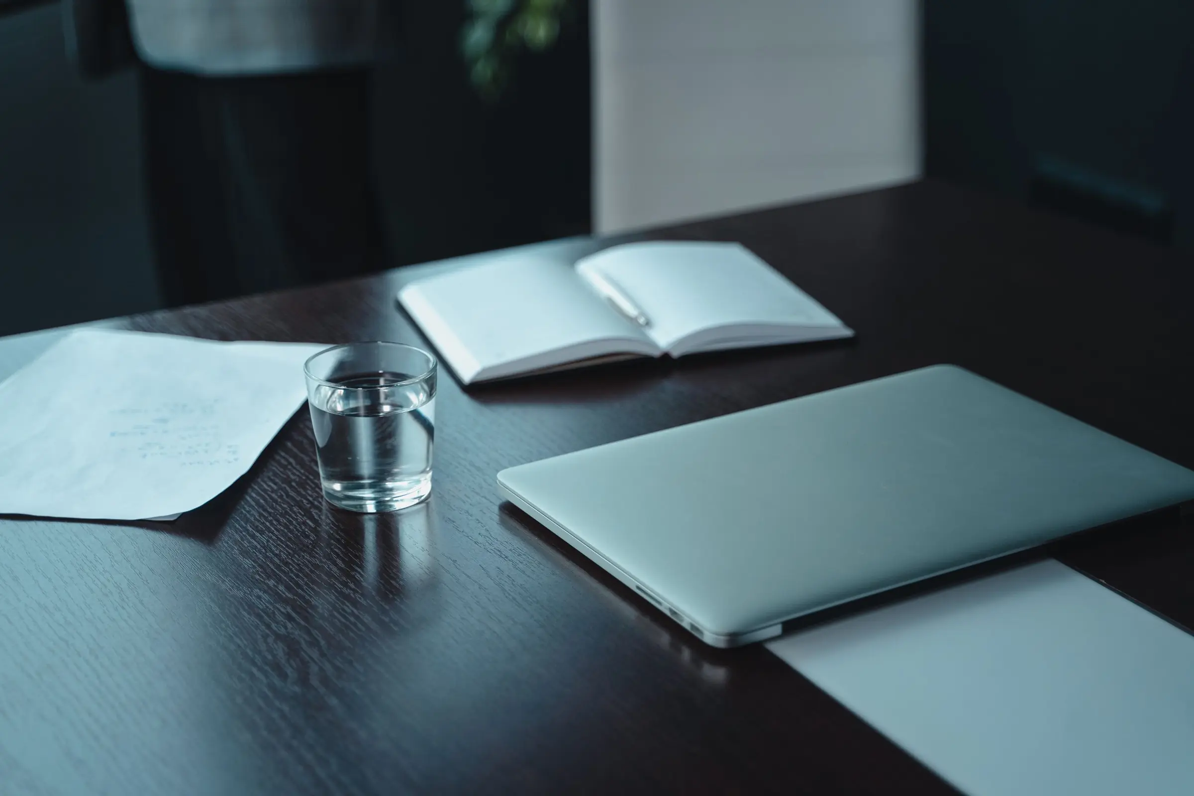 Desk with notebook and laptop in subdued light